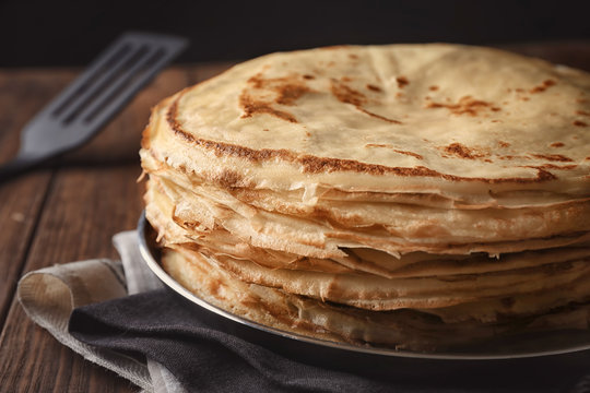 Frying pan with stack of delicious thin pancakes, closeup