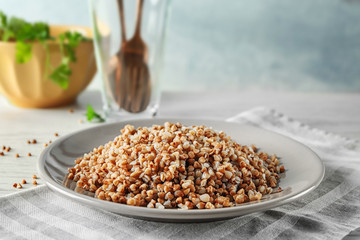 Plate with cooked buckwheat on table