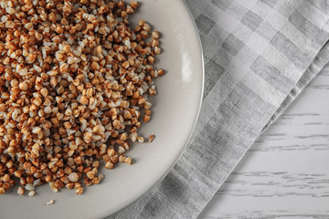Plate with cooked buckwheat on table