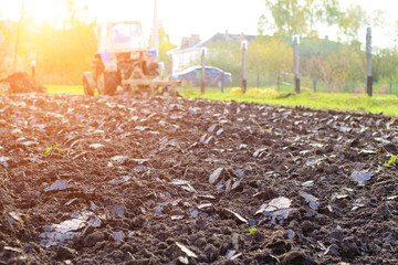 Tractor plowing a land in rays of the sun, rural life in Russia. Concept of agriculture, farming, poverty, farmland and decline