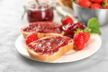 Plate with pieces of bread and strawberry jam on table