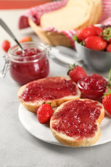 Plate with pieces of bread and strawberry jam on table