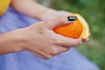 Two pieces of orange at in girl hands with black manicure.