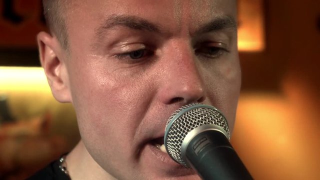 Portrait handsome musician singing song in microphone on rock consert at stage