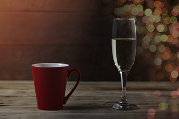Red cup and a glass of champagne on a wooden background. Bokhe