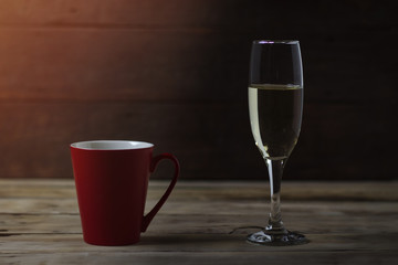 Red cup and a glass of champagne on a wooden background