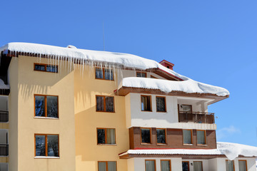 Snow-covered house. Covered with snow, hanging ice icicles