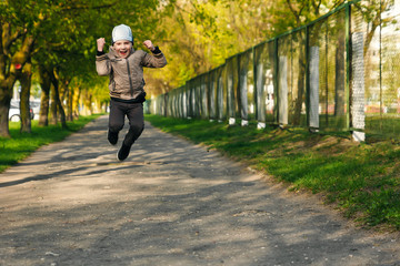 Handsome boy of six years playing, jumping, running, smiling in the park. Place for text