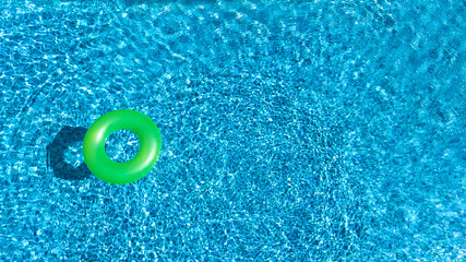 Fototapeta na wymiar Aerial view of colorful inflatable ring donut toy in swimming pool water from above, family vacation concept background 