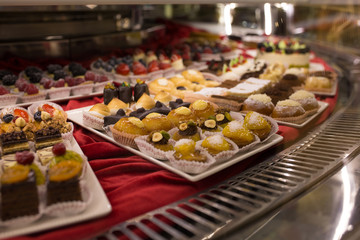 Different colorful Tasty beautiful cakes on a show-window in cafe