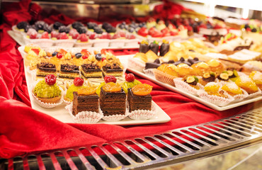 Different colorful Tasty beautiful cakes on a show-window in cafe