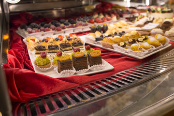 Different colorful Tasty beautiful cakes on a show-window in cafe