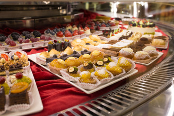 Different colorful Tasty beautiful cakes on a show-window in cafe