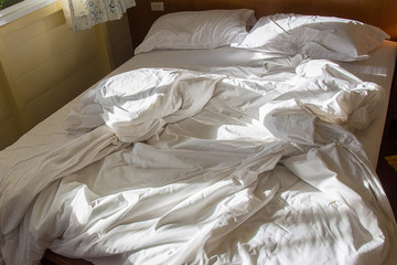 Used crumpled white bed in the morning
