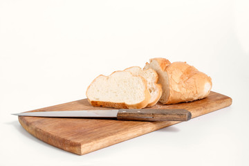 Sliced white bread lying on a kitchen board with a knife side view on a white background