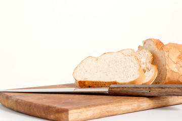 Sliced white bread lying on a kitchen board with a knife side view on a white background