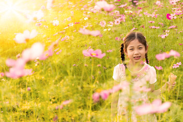 Cute little girl eating ice cream  in the field of pink flowers at sunlight