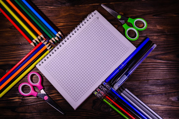 Fototapeta na wymiar Set of different school stationeries. Notepad, scissors, pensils, on wooden desk. Back to school. Top view