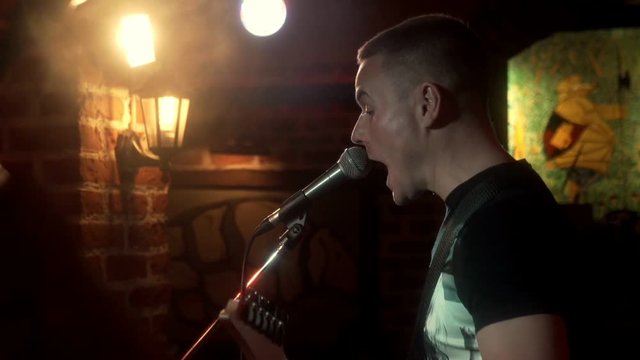 Handsome musician singing song and playing on electric guitar at music consert