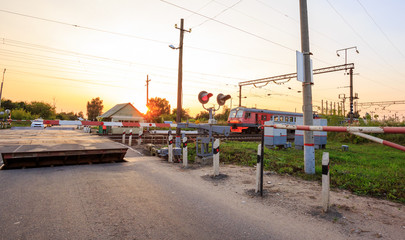 Railway crossing barrier, traffic lights and speed hump signs in rural landscape
