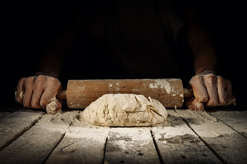 Hands rolling dough in flour
