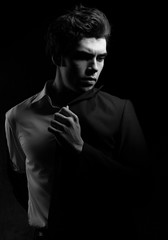 Handsome charismatic emotional man looking serious in dark shadow dramatic light. Closeup portrait. Art. Black and white