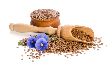 Flax seeds in the wooden bowl, wooden scoop and beauty flowers isolated on white background. Phytotherapy.