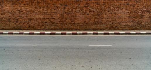 Fototapeta premium old brick wall with concrete sidewalk