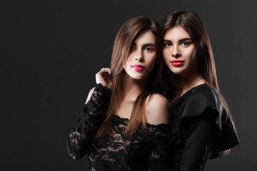 Fototapeta na wymiar two women in a black dress. Twins