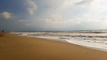 Fototapeta na wymiar Sea wave on sand beach in a cloudy day