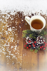 Obraz na płótnie Canvas Christmas decoratoin on wooden background. Mug of red tea decorated with snow