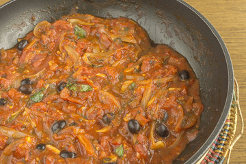 Pan with olive sauce with tomato and onion