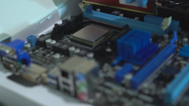 a man in blue latex gloves collects chips. production of modern computers. the hands of a person set the ditali. 4K