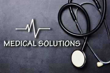 Medical solutions text on blackboard with stethoscope and heartbeat rate