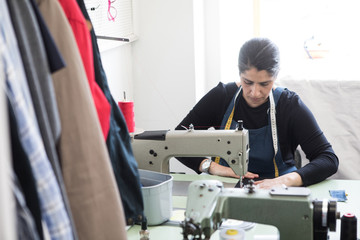 Mature female tailor using sewing machine at Laundromat