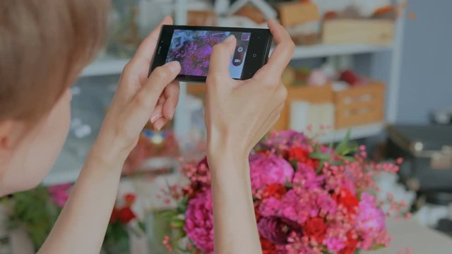 Professional floral artist, florist taking photo of her beautiful bouquet with smartphone. Close up shot of woman's hands with mobile. Photography, technology and social media concept