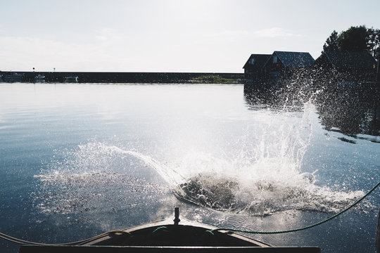 Splashing water in lake by boat against sky on sunny day
