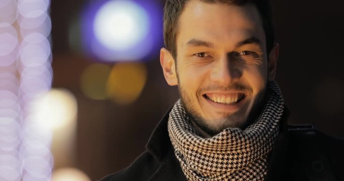 Smiling closeup portrait of happy young man in night city