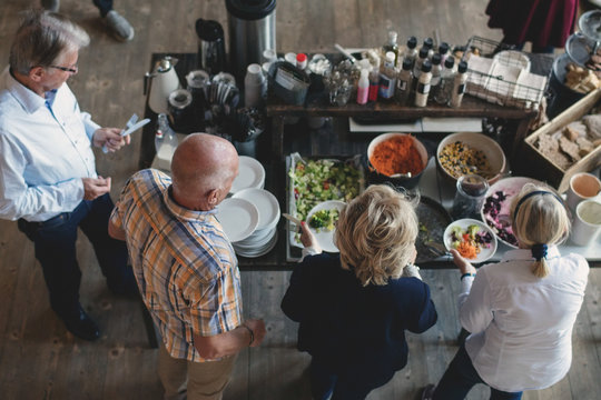 High angle view of senior male and female friends at buffet counter in restaurant