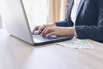 business people working with laptop in office , Notebook  laptop and Us Dollars bill on wood table , business concept