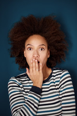 Head shot of mixed race woman with surprised face expression. Blue wall in background