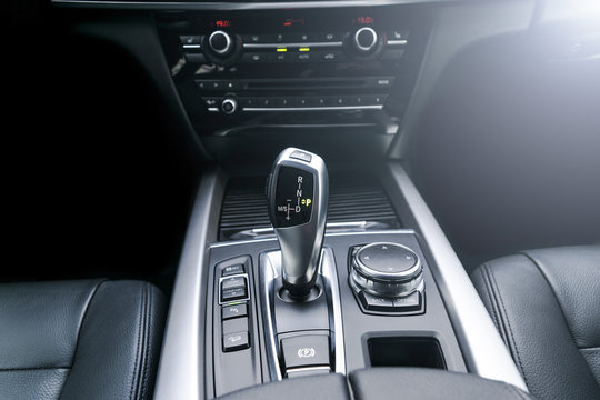 Automatic gear stick (transmission) of a modern car, multimedia and navigation control buttons. Car interior details. Transmission shift. Soft lighting