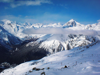 Naklejka premium Views of snow capped mountains of Dombay. Winter Sunny day, mountain range, clouds