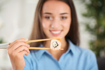 Beautiful young woman with sushi roll at home