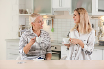 Obraz premium Young woman drinking tea with elderly mother at home