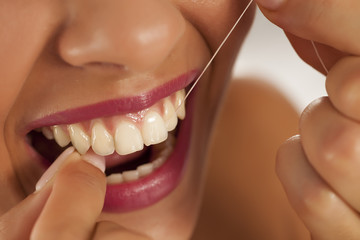 young beautiful woman cleans her teeth with dental floss