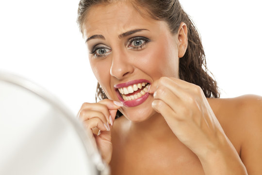 young nervous woman cleans her teeth with dental floss