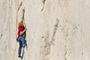 Obraz na płótnie Canvas A climber man climbs to the top of a cliff.