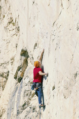 Obraz na płótnie Canvas A climber man climbs to the top of a cliff.