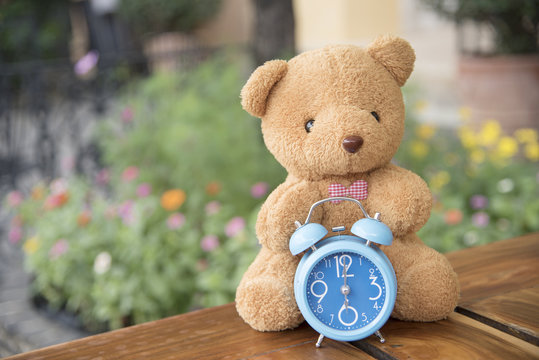 Teddy bear with blue clock on backdrop